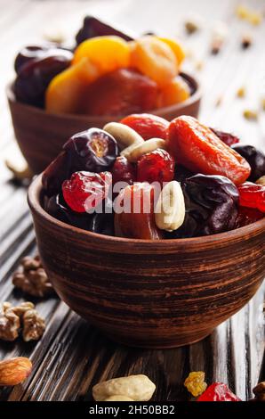 Dried apricots dates cashews and cherries in clay bowl on wooden kitchen table closeup Stock Photo