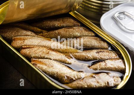 Canned smoked fish sprats in just opened tin can. Non-perishable food Stock Photo