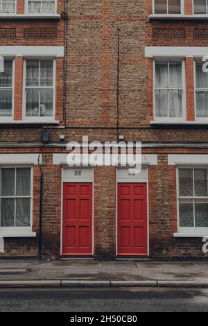 London, UK - October 17, 2021: Traditional red front doors on an apartment block in Victoria Buildings in Southwark, London. Bright coloured doors are Stock Photo