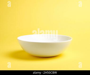 Empty white ceramic bowl on yellow background Stock Photo