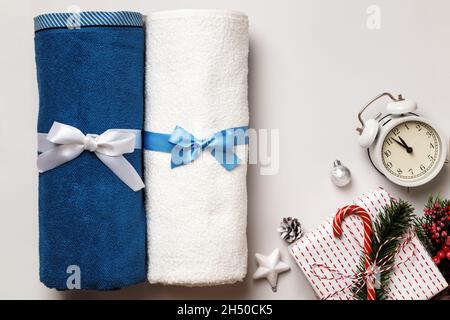 Fresh white and blue terry towel with a bow rolled up on a light gray background. Gift alarm clock Christmas tree decorations. Copy space Stock Photo