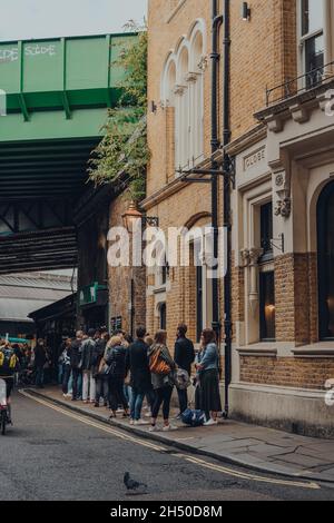 London, UK - October 17, 2021: People queuing for take away food inside Borough Market, one of the largest and oldest food markets in London. Stock Photo