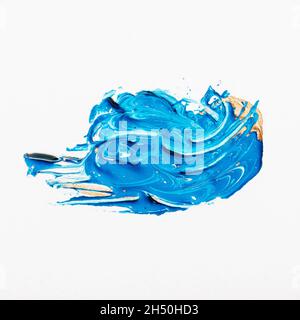 Abstract smear of blue paint mixed with white and gold on white background, macro Stock Photo