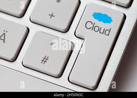 Bright computer keyboard with enter key and the word cloud and a blue cloud Stock Photo