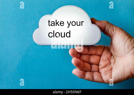 Hand holds a white cloud symbol against a blue background. The text is written on the cloud: take your cloud. Stock Photo