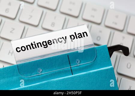 contingency plan is on a label of a blue hanging file. In the background a computer keyboard Stock Photo