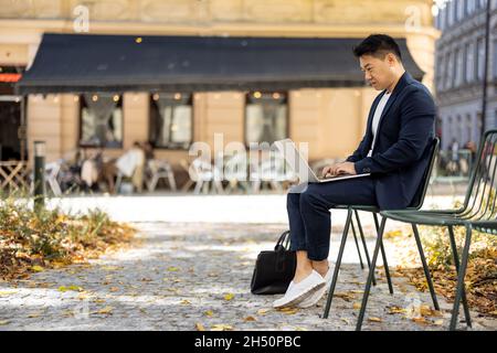 Businessman typing on laptop during work outdoors Stock Photo