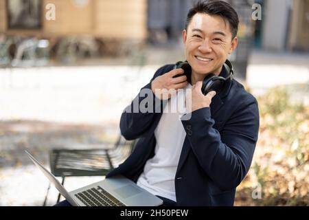 Asian business man working on laptop outdoors Stock Photo