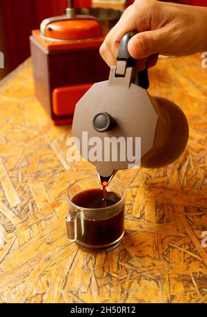 Hand pouring freshly brewed aromatic espresso from the coffee pot Stock Photo