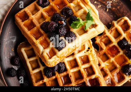 Flat lay view at homemade crispy Belgian waffles served with blackberries and honey closeup Stock Photo