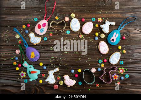 Sugar sprinkles, candies, cookie cutters, sewed felt toys and cookies in shape of egg chicken and rabbit on wooden table background. Flat lay mockup w Stock Photo