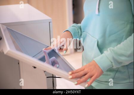 Faceless woman touching the screen of a self-service device in a store. Device store navigator. Self purchase. Stock Photo