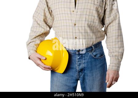 Middle aged caucasian contractor weared in blue jeans and shirt holds yellow hard hat in his hands on white background Stock Photo