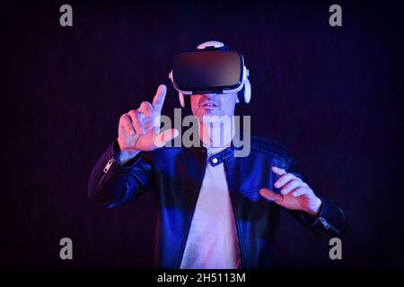 Man having fun dressed casual interacting with virtual reality glasses with dark isolated background Stock Photo