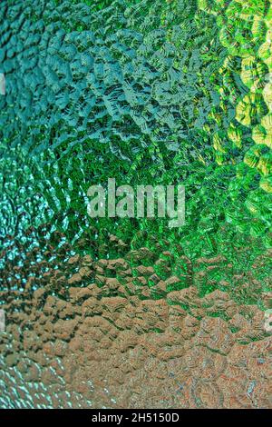 Detail of a view through a window with patterned glass. Abstract pattern in shades of yellow, green, brown and grey Stock Photo