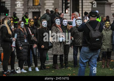 Westminster, London, UK. 5th Nov, 2021. Protesters from the annual Million Mask March mix with Anti-Lockdown and Anti-Vaccination protesters, some also in Guy Fawkes masks, on Parliament Square in Westminster this afternoon and evening. Flares and some fireworks are lit, prompting police to take a cautious stance with strong police presence throughout Westminster tonight. Credit: Imageplotter/Alamy Live News Stock Photo