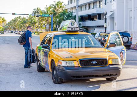 Miami Beach Florida,Ocean Drive,taxi cab man male,passenger rider stopped pick picking up middle of street safety Stock Photo