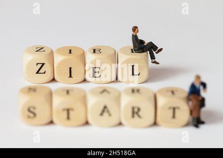 Small plastic figures with words made from letter cubes. The German word for goal and for start can be read Stock Photo