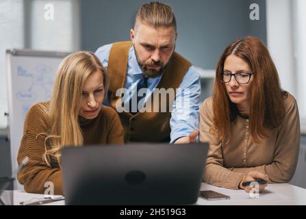 Three office workers using laptop Stock Photo