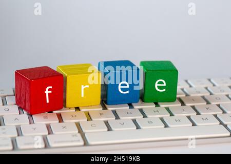 The letters free was written on blocks. These letters are written in white on red, yellow, blue and green blocks and stand on a bright computer keyboa Stock Photo