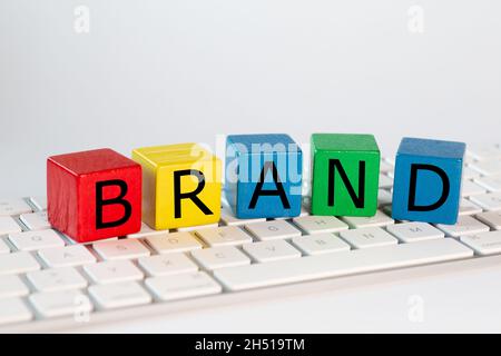 The letters BRAND was written on blocks. These letters are written in black on red, yellow, blue and green blocks and stand on a bright computer keybo Stock Photo