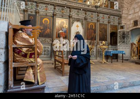 A Greek orthodox priest speaks with an eastern orthodox nun at the Chapel of St John and baptistry at the courtyard of the Orthodox Chapel of St James also named Church of Mar Jacob or St Jacob's Orthodox Cathedral located next to the Church of the Holy Sepulcher, on the Western wall of the square.in the Christian Quarter old city  East Jerusalem Israel Stock Photo