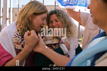 A member of the Women of the Wall holds a Torah scroll, as security forces hold back Ultra-Orthodox Jews protesting their prayer at the Western Wall on November 05, 2021 in Jerusalem, Israel. The Women of the Wall is a feminist prayer group that holds a monthly prayer session at the Western Wall and have consistently claimed that there is no single 'custom of the place' and that their right to pray is a religious freedom enshrined in Israeli law Stock Photo