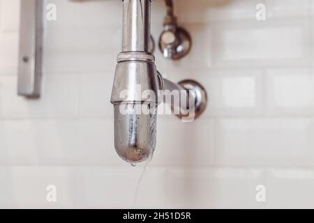 Leakage of water from steel modern siphon in bathroom. Problems with gasket. Stock Photo