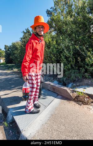 Rand, the street person, dressed in bright colors of red and orange, walks along State Street in Santa Barbara County with his very tall orange hat.