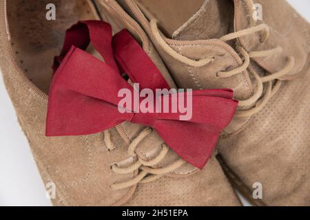 Groom accessories. Shoes on a white background with red butterfly suede shoes. View from above, bokeh. Stock Photo