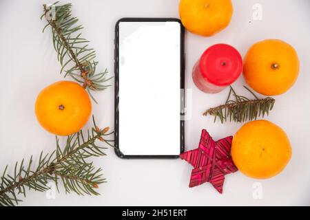 Merry Christmas. special Christmas greeting text on a mobile phone screen on a white background with decorations and tangerines Stock Photo