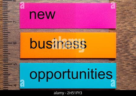 Three bookmark stickers with the words new business opportunities, on a dark natural wooden table Stock Photo