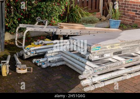 Pile of components of hired scaffolding or mobile platform work tower in domestic garden Stock Photo