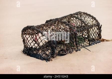 A discarded lobster trap or pot washed ashore onto a beach Stock Photo