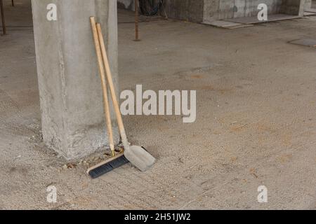 Shovel and broom for construction site cleaning. Tool for cleaning construction waste. Cleanliness at the construction site. Cleaning of construction Stock Photo