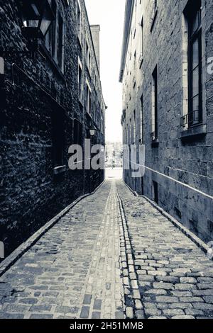 Black and white photo of an empty narrow street in Old Montreal Alley Stock Photo