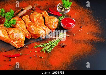 Convenience food, precooked.Raw Marinated chicken meat legs with spices for cooking for BBQ dark background. Top view. Stock Photo