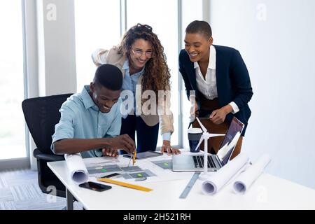 Smiling multiracial male and female architects working on blueprint in office Stock Photo