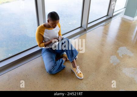 Creative businesswoman text messaging through smartphone while sitting on floor in office Stock Photo