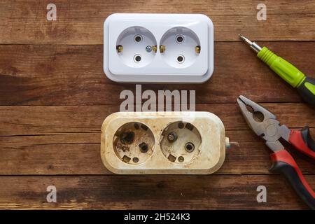 Burnt out electrical outlet and new to replace on a wooden background Stock Photo