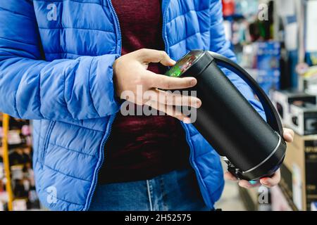 Close up on midsection of unknown caucasian man standing in the electronics store holding wireless speaker copy space Stock Photo