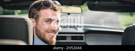 Car driving man driver smiling portrait. Young adult sitting in front seat of new convertible sports car. Panoramic header crop banner. Stock Photo