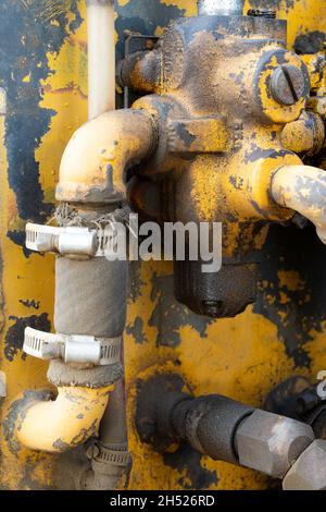 Old rusty yellow tractor hydraulic manifold Stock Photo