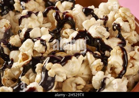 Closeup sweet popcorn with chocolate sauce on a pink background Stock Photo
