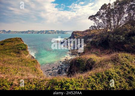 Seascape with the rocky shore in spring. View of Ria de Ribadeo del Eo bay. Puente de Los Santos bridge on the horizon. Ribadeo, Spain Stock Photo