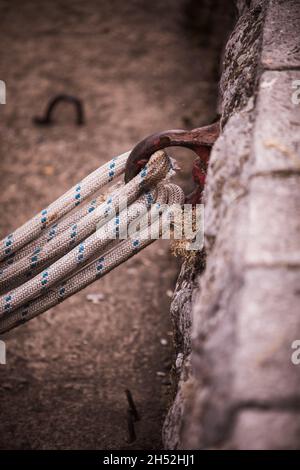 Old rusty metal mooring ring on the mooring wall with ropes tied to it. Stock Photo