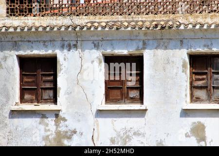 Old shuttered windows in a cracked whitewashed wall, Spain Stock Photo