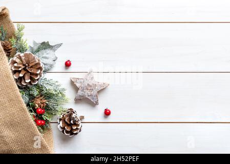 Christmas composition on a white wooden table with a sack from which decorations come out. Free space beside for greeting text Stock Photo