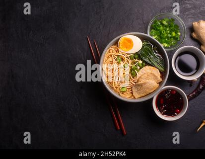 Ramen is asian noodles in a bowl with meat and vegetables or seafood, often flavored with soy sauce or miso. Dark background with copy space Stock Photo