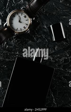 Men's watches and an open bottle of black eau de toilette lie on a dark textured background. Fragrance for men. flat lay Stock Photo